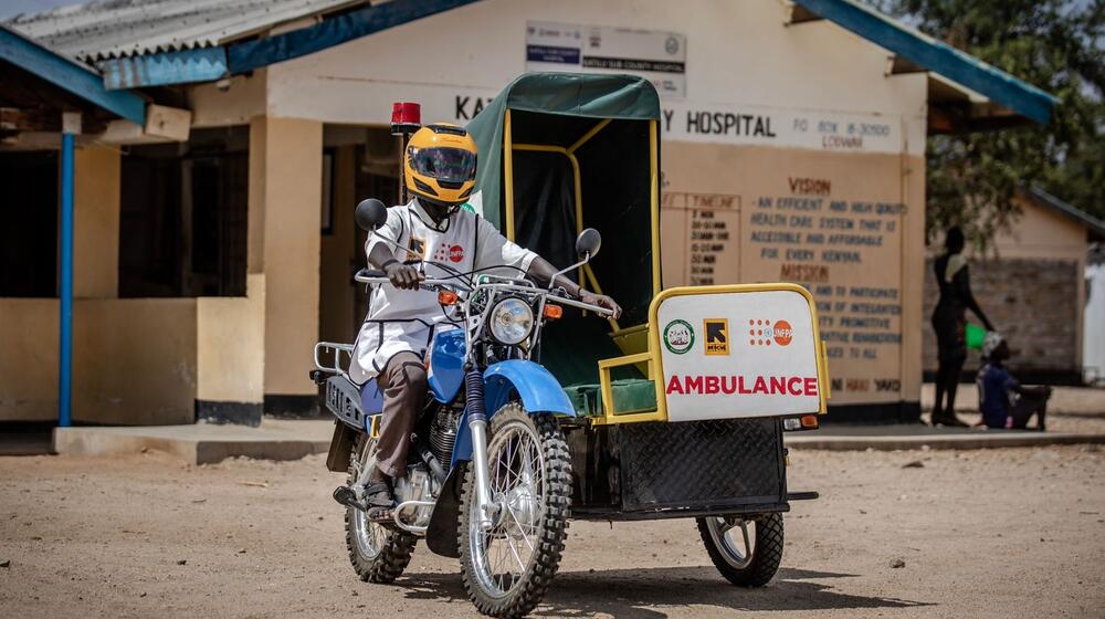 A healthcare worker rides a motorbike ambulance.