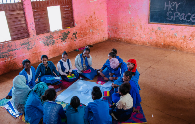 Group of young girls sitting in a circle, laughing and conversing.