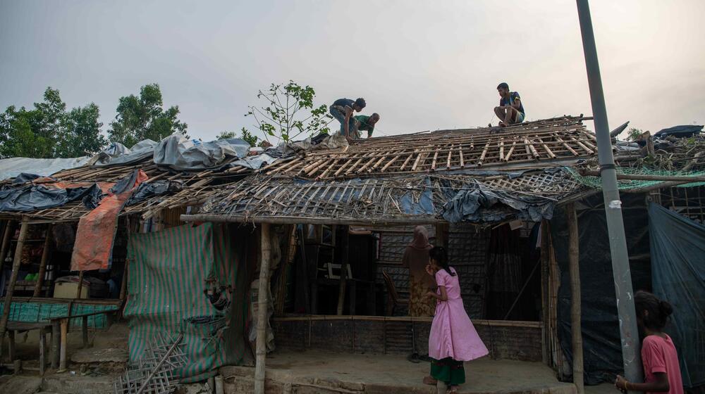 People repair the roof of a damaged building.