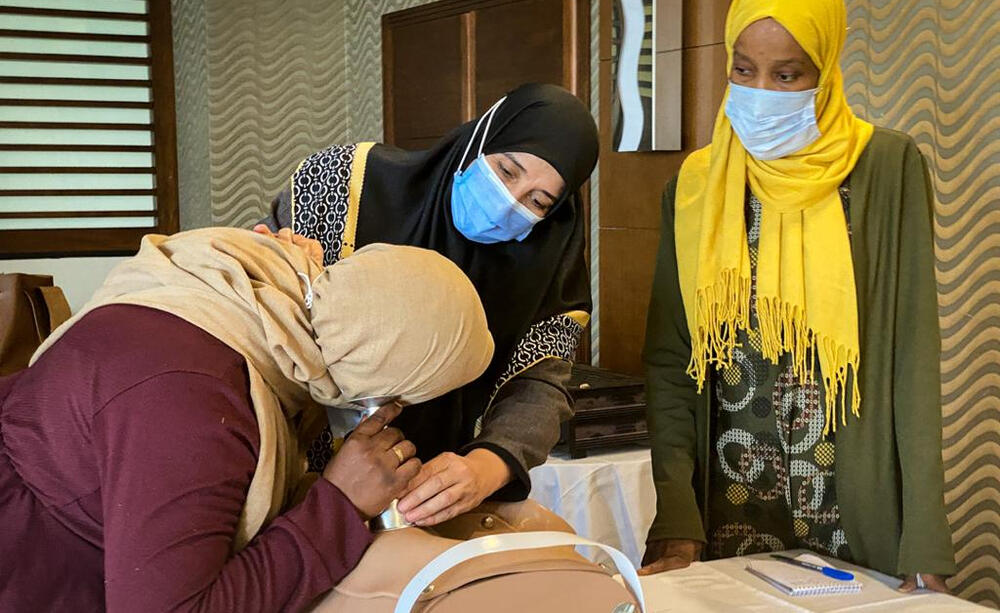 Two women are taught how to use medical tools during midwifery training.