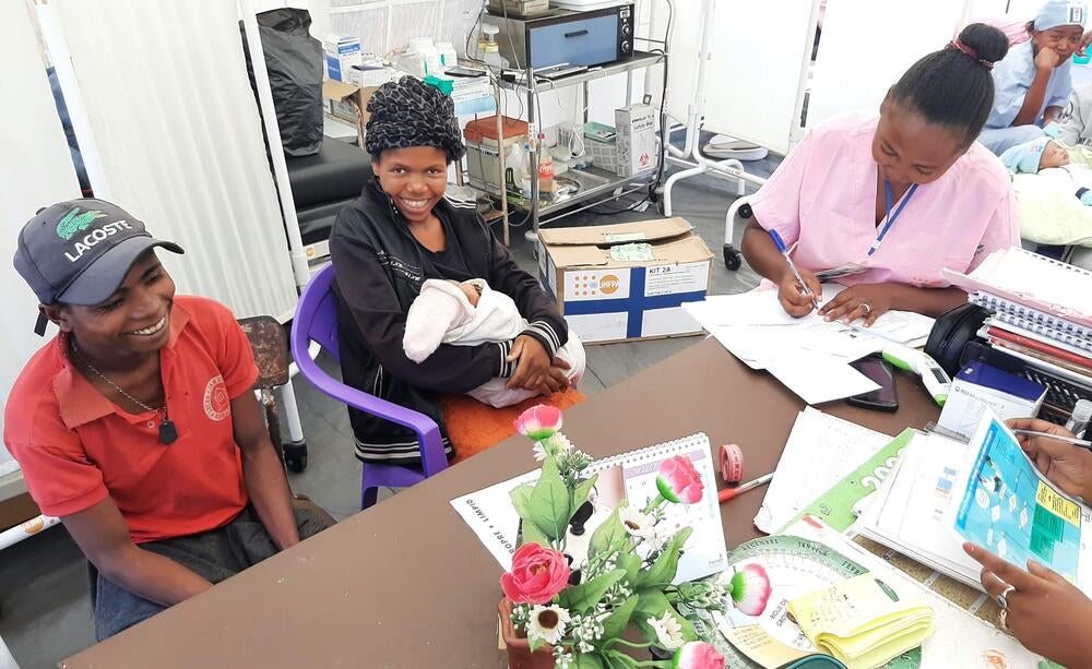 A new mother smiles as she receives medical support.