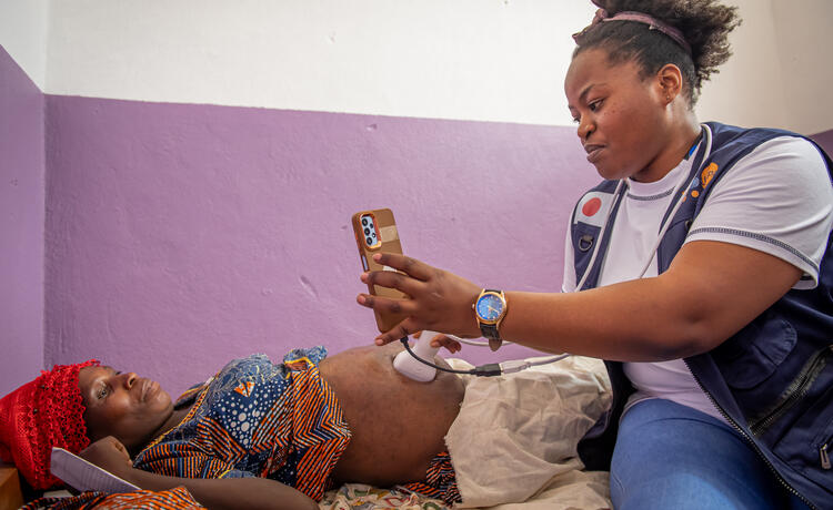 A UNFPA midwife uses a mobile phone screen to show a woman an ultrasound scan of her womb. 