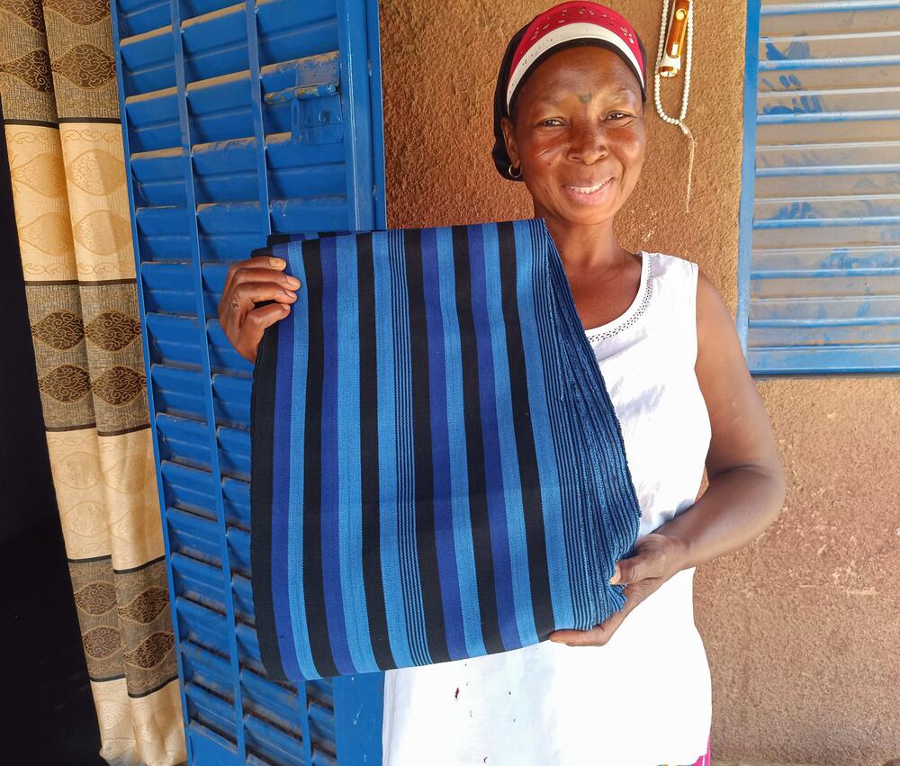 A woman shows her hand-made textile to the camera.