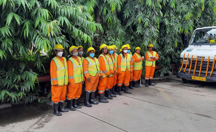 Women cleaners stand in a row beside machine