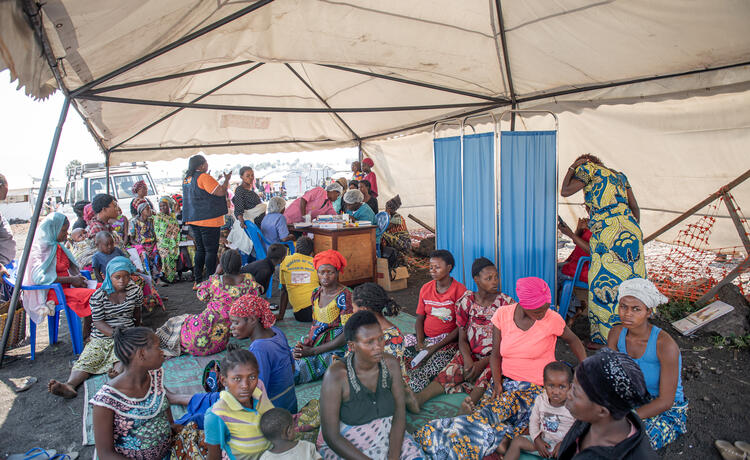 Un grand groupe de personnes assises dans une clinique mobile soutenue par l’UNFPA, dans le camp pour PDIP de Bulengo.