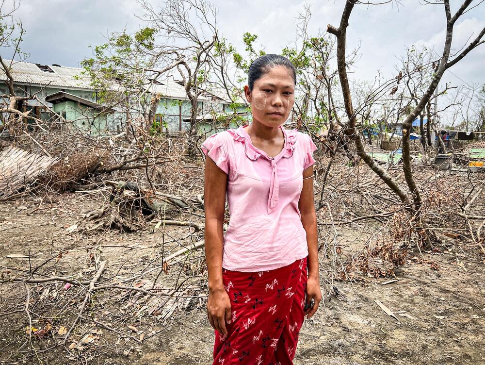 A woman stands in front of trees torn down by the cyclone. 