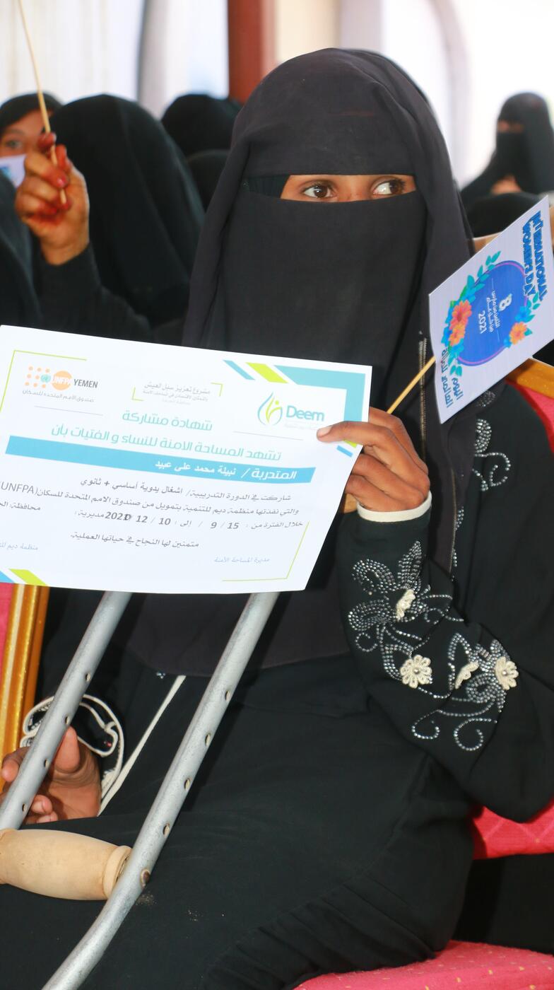 A woman holds a training certificate.