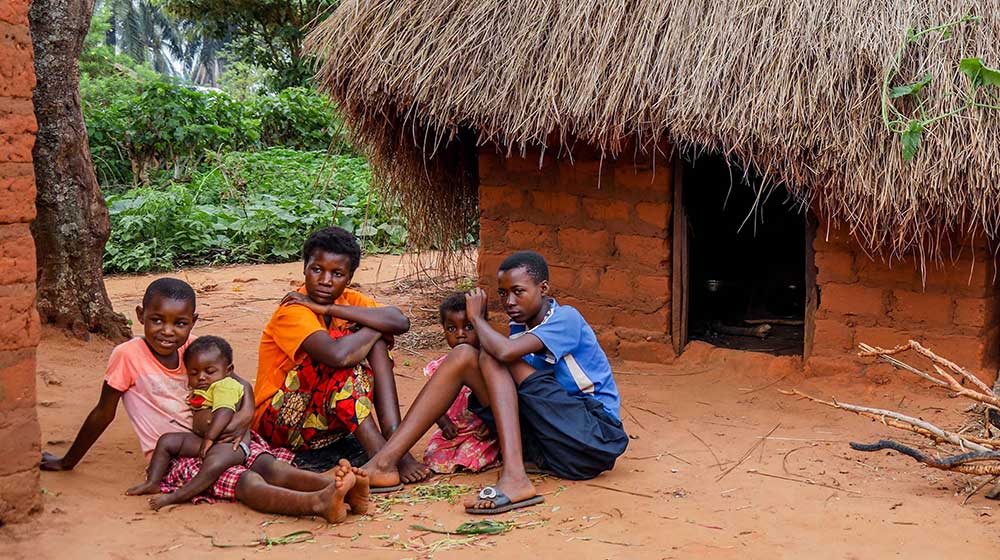 Les enfants de Mme Malu sont assis dans leur petite cour sur le sol de terre rouge.