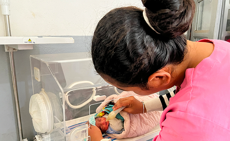  A midwife attends to a newborn baby in an incubator.