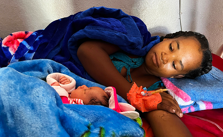 Une patiente est allongée sur un lit en compagnie de son nouveau-né.