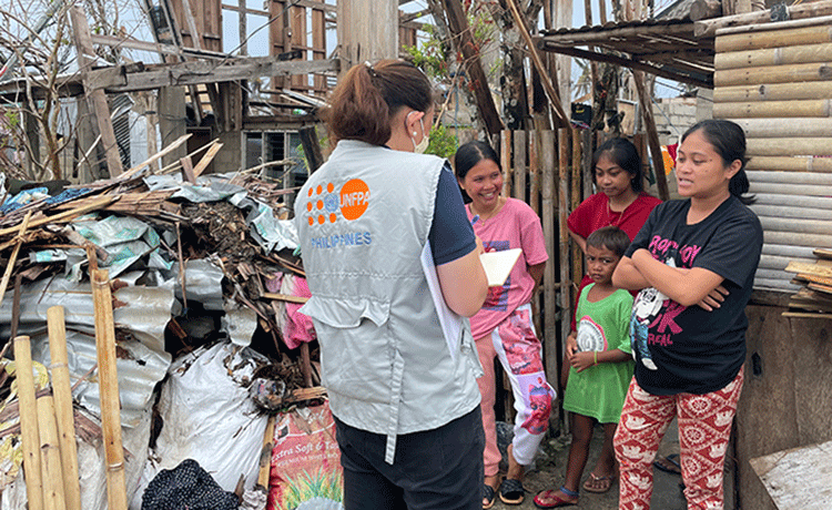 Un miembro del personal del UNFPA camina hacia un edificio dañado en Filipinas