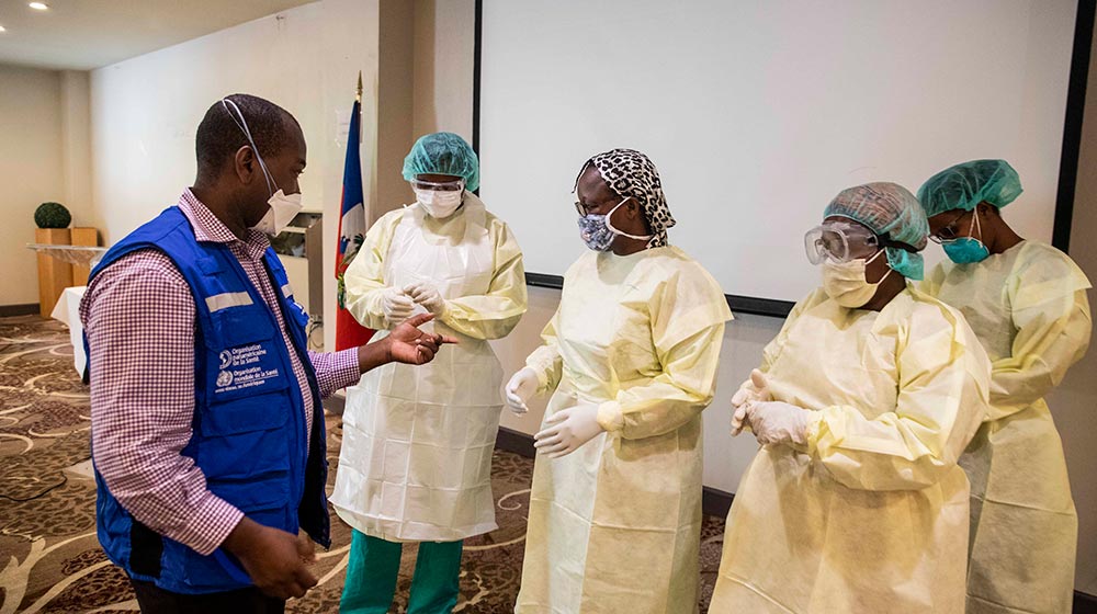 Health workers try on personal protective equipment, including bonnets, face masks, goggles, gowns and gloves, at a demonstration in Haiti. 