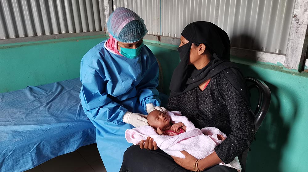 Midwife Rotna provides care to MInara's newborn baby at a UNFPA-supported health centre.