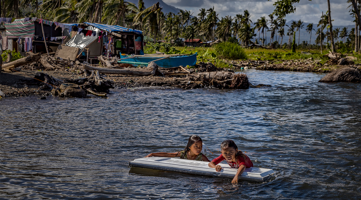 Des enfants flottent sur une rivière en crue, accrochées à des déchets, après le passage du typhon Rai à Saint Bernard (Philippines), en 2022. © UNFPA Philippines/Ezra Acayan