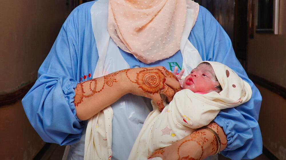 A newborn baby in a medical worker's arms.