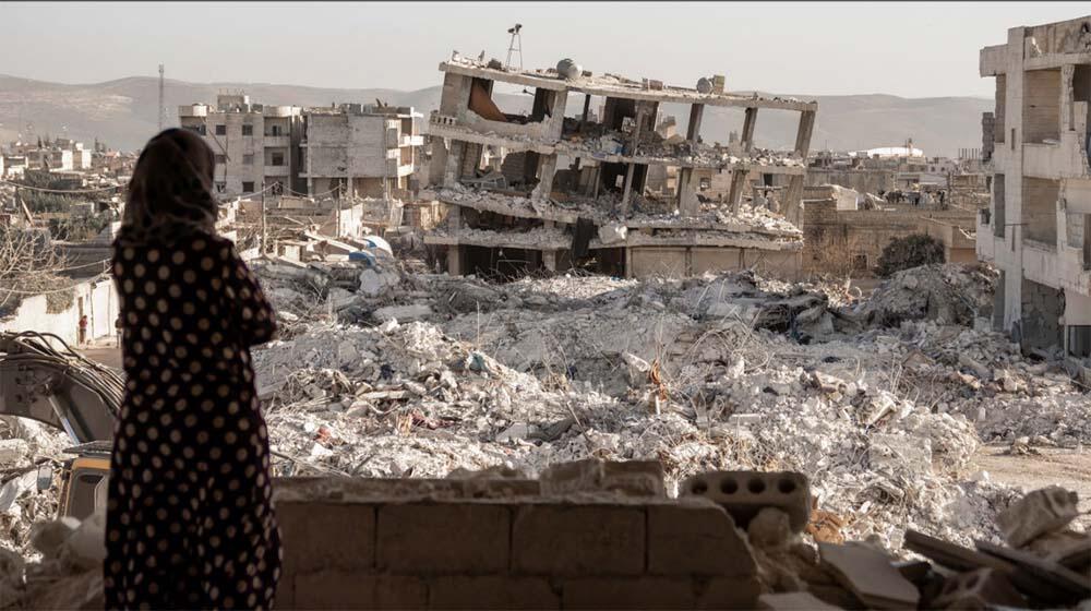 Woman in polka dot dress glances out and views destruction left by the Turkiye-Syria earthquake