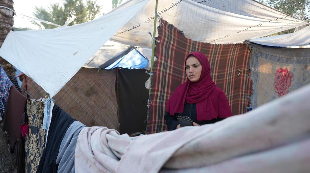 An internally displaced woman stands in front of a camp tent near the Nasser Hospital in Khan Yunis, southern Gaza Strip.
