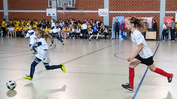 Two girls competing in an indoor soccer match.