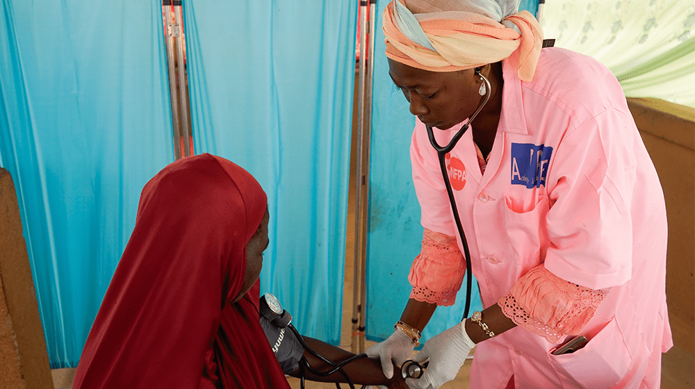 UNFPA-trained nurse checking woman's blood pressure in a clinic in Niger.