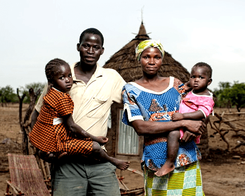 A family with two small children in front of their home.