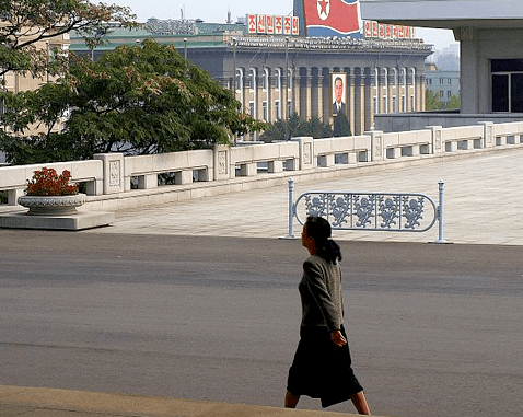 A woman walks past a government building.