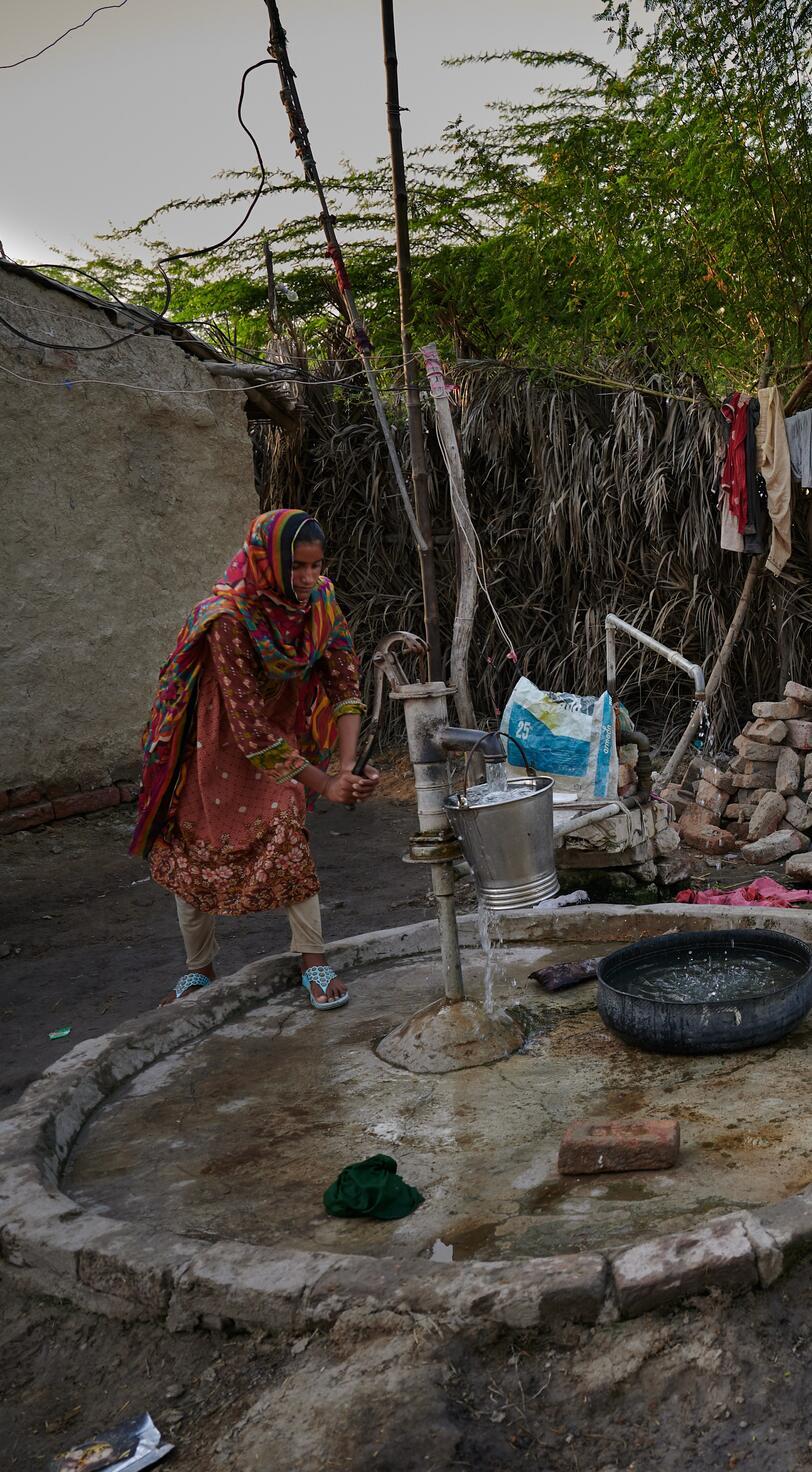 A woman pumps water from a well.