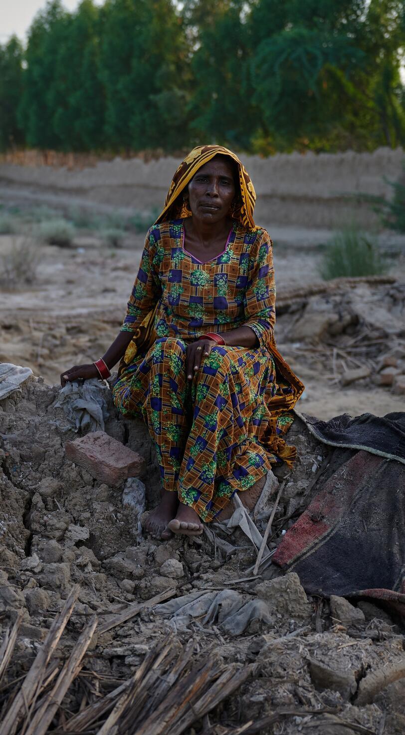 A woman sits on the remains of her home.