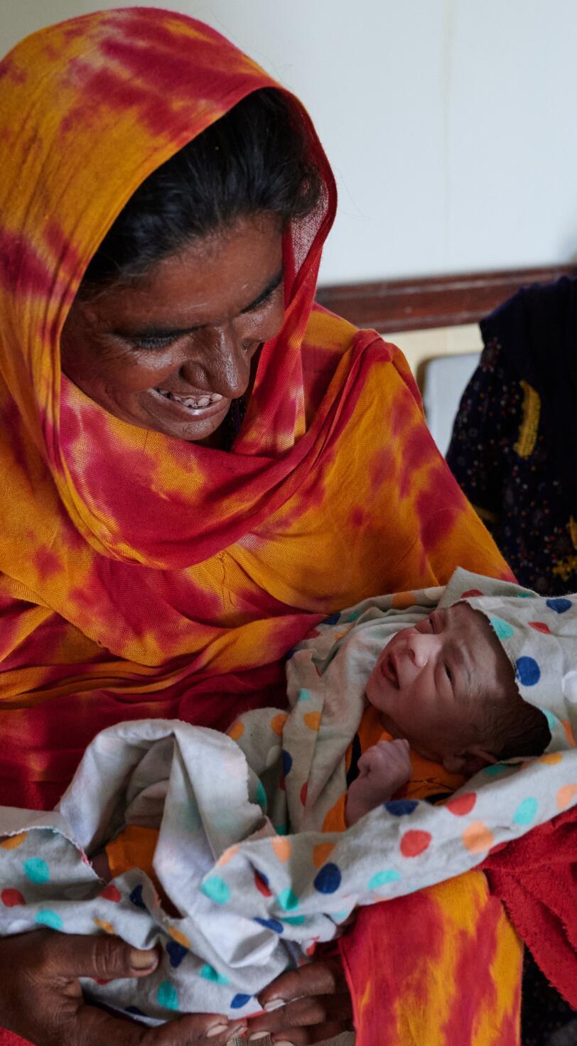 A woman smiles at her newborn child.