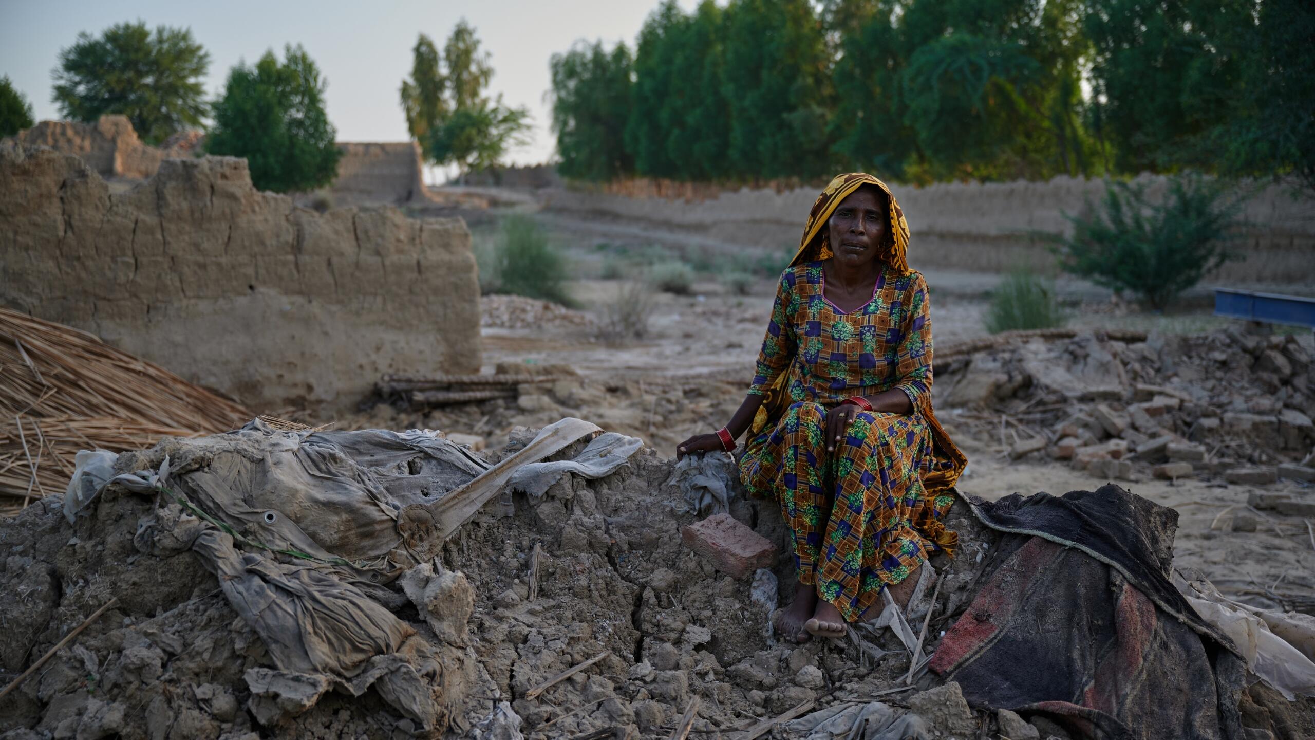 A woman sits on the remains of her home.