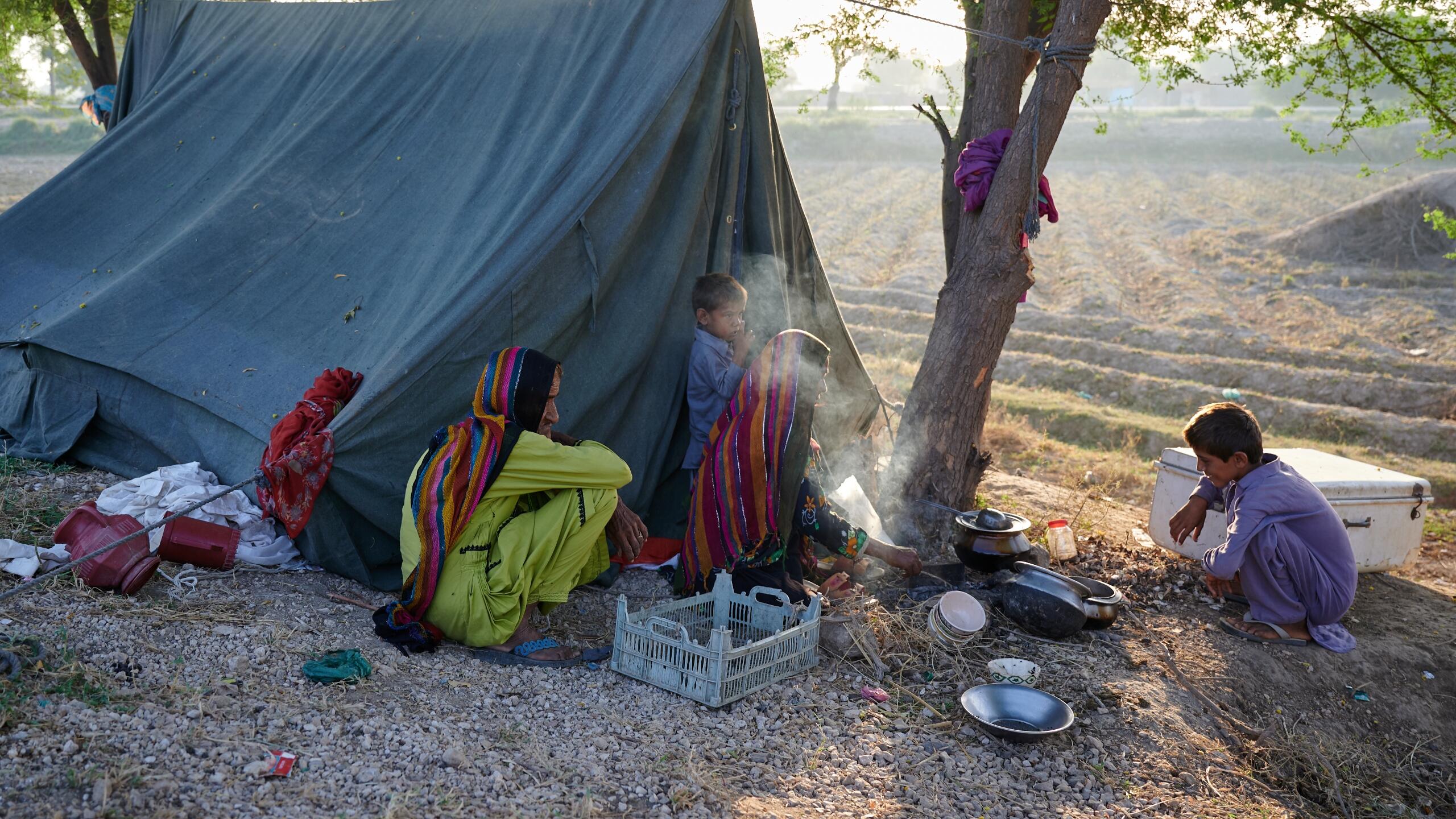 A family cooks by a tent.
