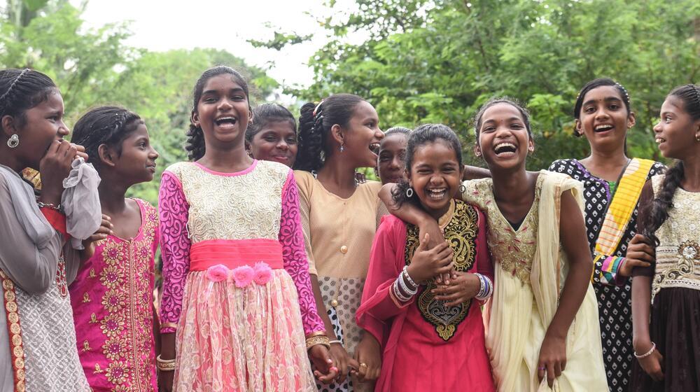 A group of girls stand together and smile. 