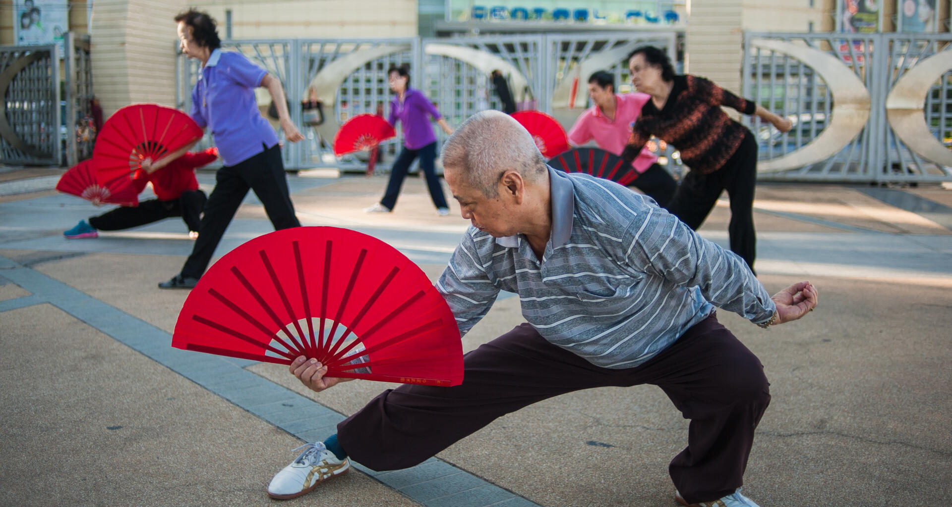 A group of elderly people perform with colourful fans.