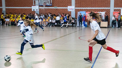 Two girls competing in an indoor soccer match.