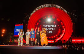Dr. Kanem addressing audience on global citizen stage. She is in orange. She stands along side three other women.